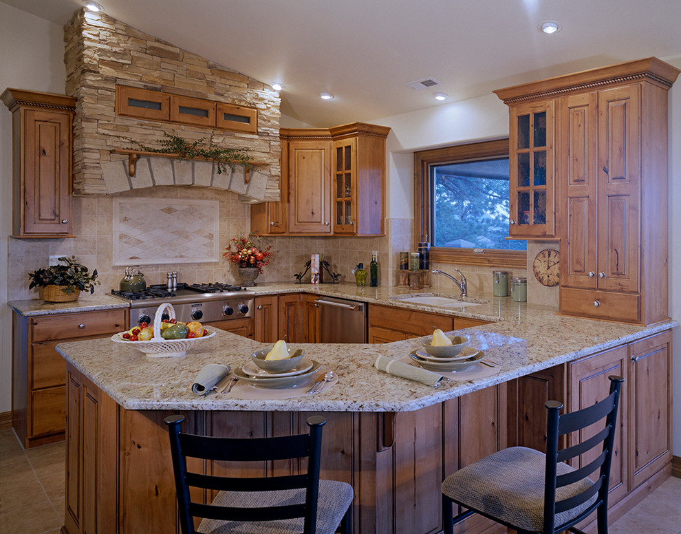 This is an example of a mid-sized country u-shaped eat-in kitchen in Denver with a double-bowl sink, raised-panel cabinets, distressed cabinets, granite benchtops, beige splashback, ceramic splashback, stainless steel appliances, ceramic floors and a peninsula.