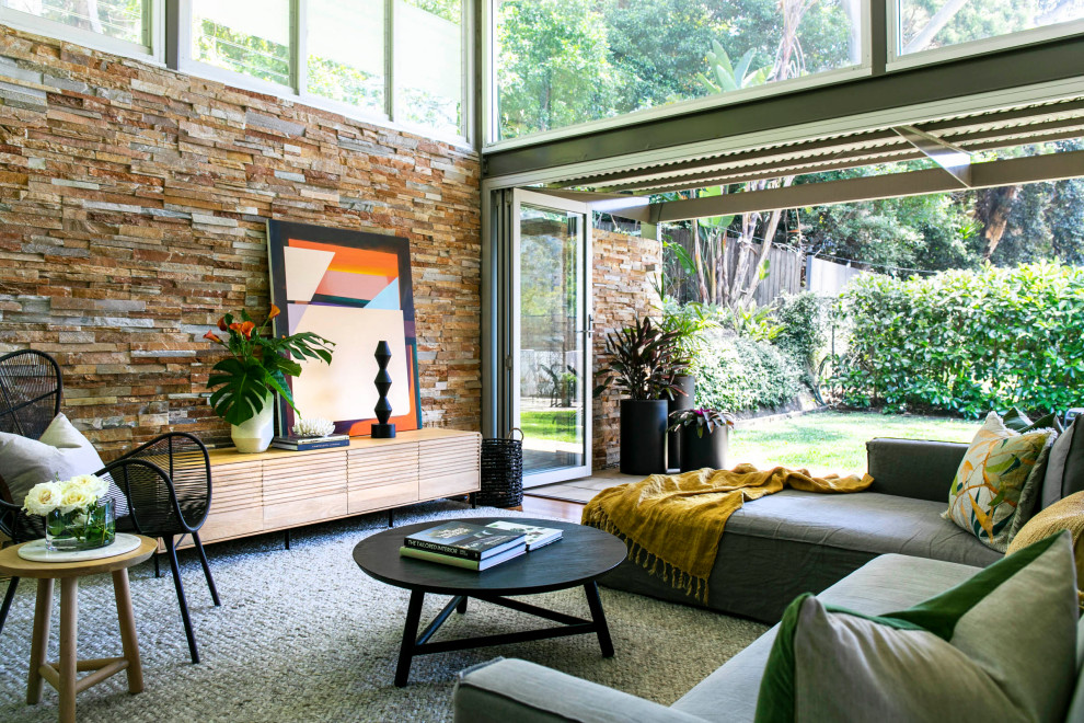 На фото: открытая гостиная комната среднего размера в современном стиле с ковровым покрытием, серым полом и кирпичными стенами с