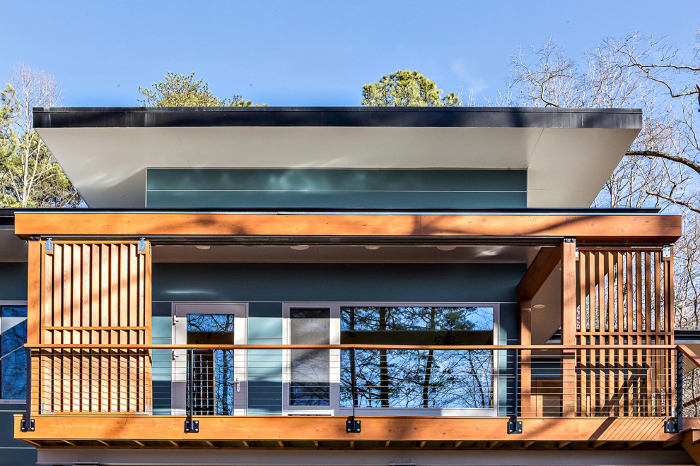 Photo of a mid-sized midcentury one-storey blue house exterior in Raleigh with concrete fiberboard siding, a flat roof and a green roof.