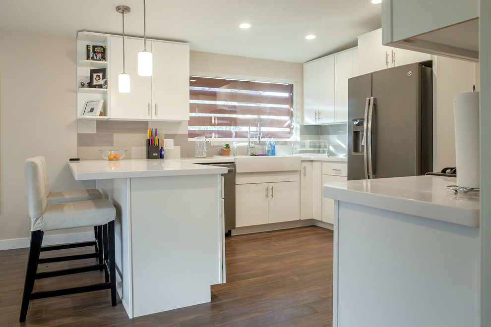 Example of a transitional u-shaped porcelain tile open concept kitchen design in Phoenix with a farmhouse sink, shaker cabinets, white cabinets, quartz countertops, multicolored backsplash, porcelain backsplash, stainless steel appliances and an island