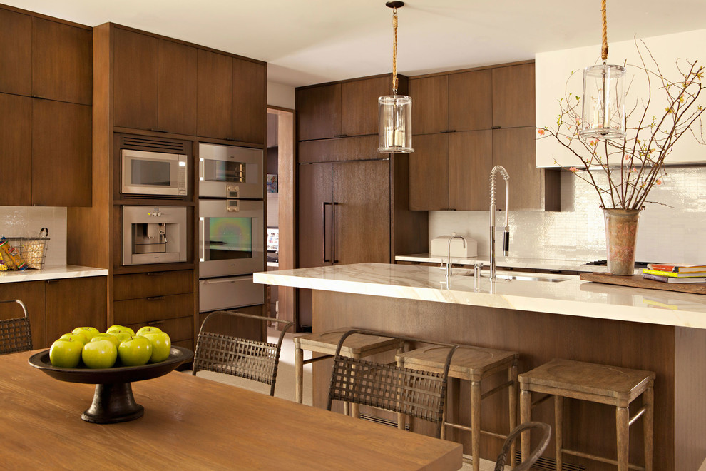 Photo of a contemporary eat-in kitchen in Los Angeles with flat-panel cabinets, dark wood cabinets, white splashback and stainless steel appliances.