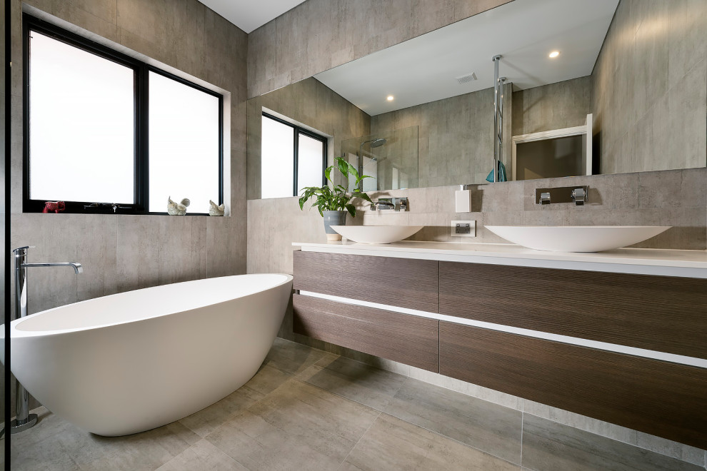 Photo of a mid-sized modern kids bathroom in Perth with flat-panel cabinets, dark wood cabinets, a freestanding tub, a curbless shower, a one-piece toilet, brown tile, porcelain tile, brown walls, porcelain floors, a console sink, engineered quartz benchtops, brown floor, an open shower, white benchtops, a double vanity and a floating vanity.
