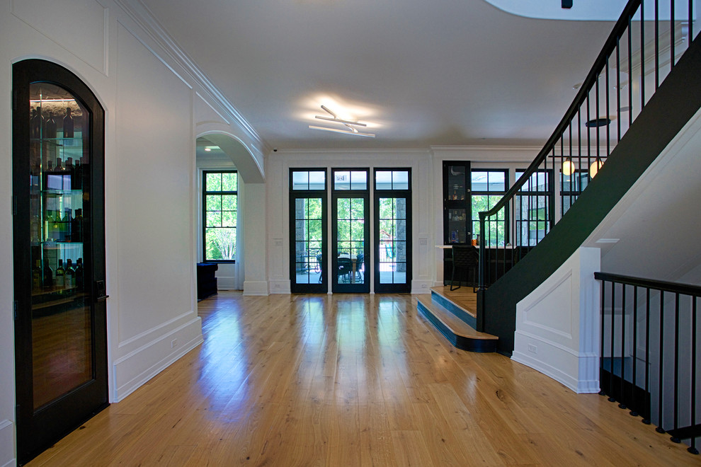 Photo of a large transitional hallway in New York with white walls, medium hardwood floors and brown floor.