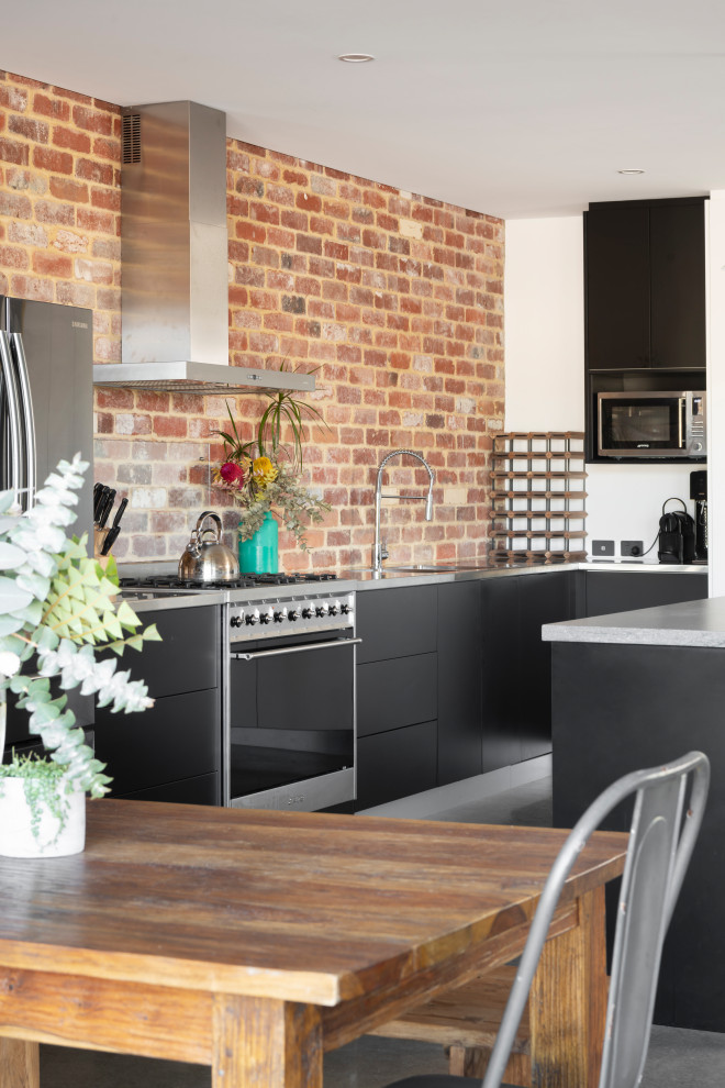 Mid-sized contemporary galley open plan kitchen in Perth with an undermount sink, flat-panel cabinets, black cabinets, concrete benchtops, red splashback, brick splashback, stainless steel appliances, concrete floors, with island, grey floor and grey benchtop.