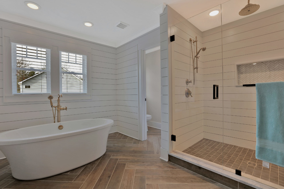 This is an example of a country master bathroom in Richmond with shaker cabinets, black cabinets, a freestanding tub, an alcove shower, a one-piece toilet, white tile, multi-coloured walls, light hardwood floors, a pedestal sink, marble benchtops, beige floor and a hinged shower door.