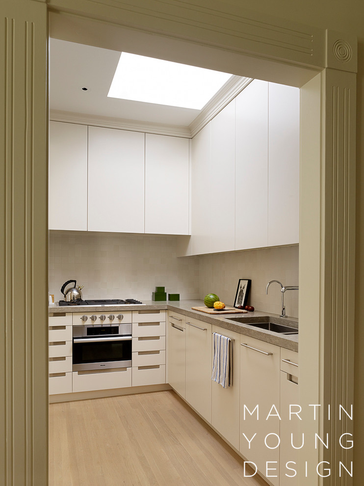 Contemporary l-shaped enclosed kitchen in San Francisco with a submerged sink, flat-panel cabinets, limestone worktops, ceramic splashback and integrated appliances.