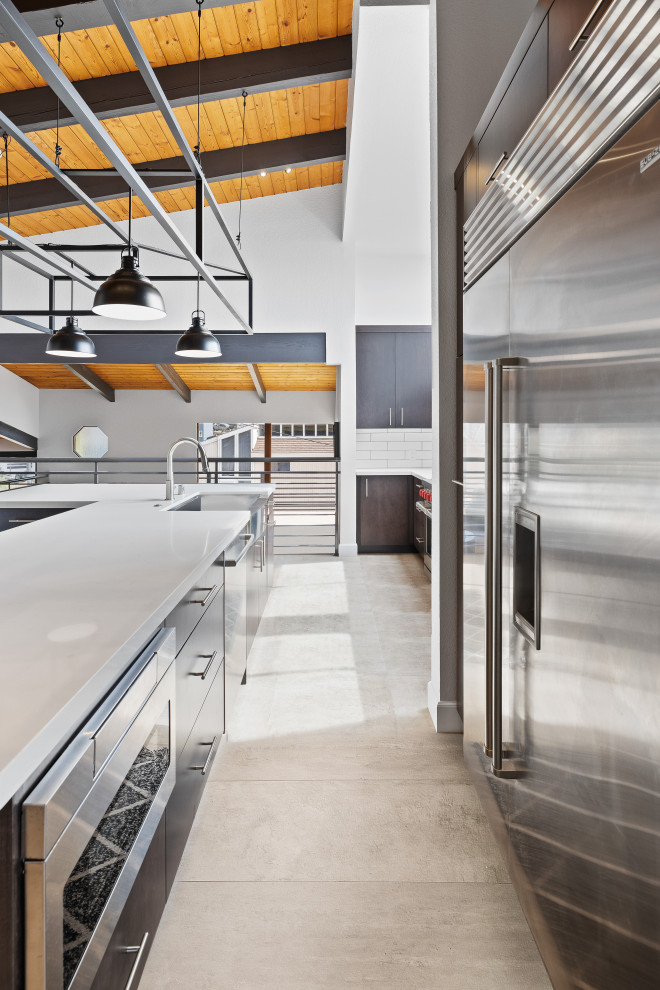 Inspiration for a contemporary l-shaped eat-in kitchen in Orange County with an undermount sink, flat-panel cabinets, black cabinets, quartz benchtops, white splashback, subway tile splashback, stainless steel appliances, porcelain floors, with island, grey floor, white benchtop and vaulted.