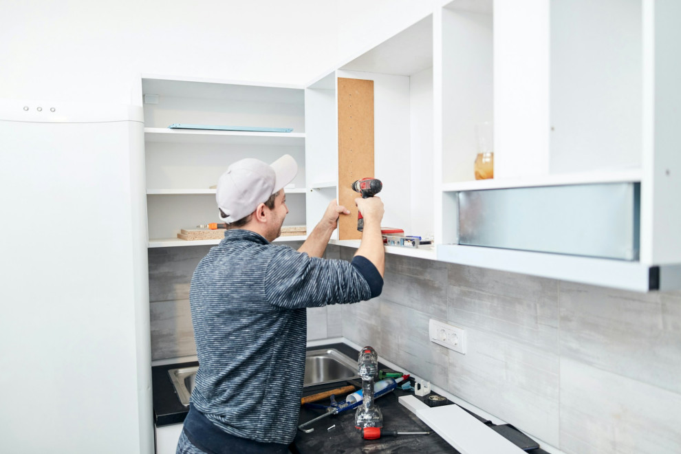 A man fixing a kitchen cabinet