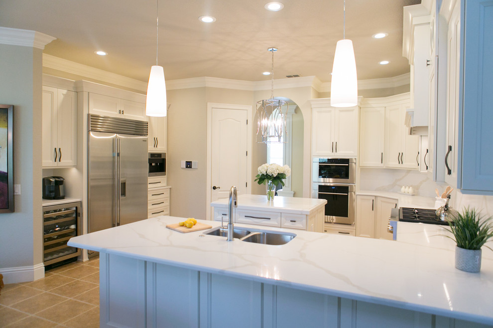 Open concept kitchen - mid-sized transitional u-shaped open concept kitchen idea in Orlando with an undermount sink, recessed-panel cabinets, white cabinets, quartzite countertops, white backsplash, stone slab backsplash, stainless steel appliances and a peninsula