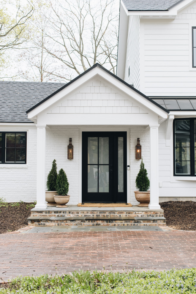 Стильный дизайн: двухэтажный, белый частный загородный дом в стиле фьюжн с комбинированной облицовкой, двускатной крышей, крышей из смешанных материалов, черной крышей и отделкой планкеном - последний тренд