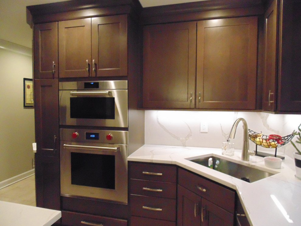 Mid-sized transitional u-shaped ceramic tile and beige floor eat-in kitchen photo with an undermount sink, recessed-panel cabinets, dark wood cabinets, quartz countertops, white backsplash, stone slab backsplash, stainless steel appliances, an island and white countertops