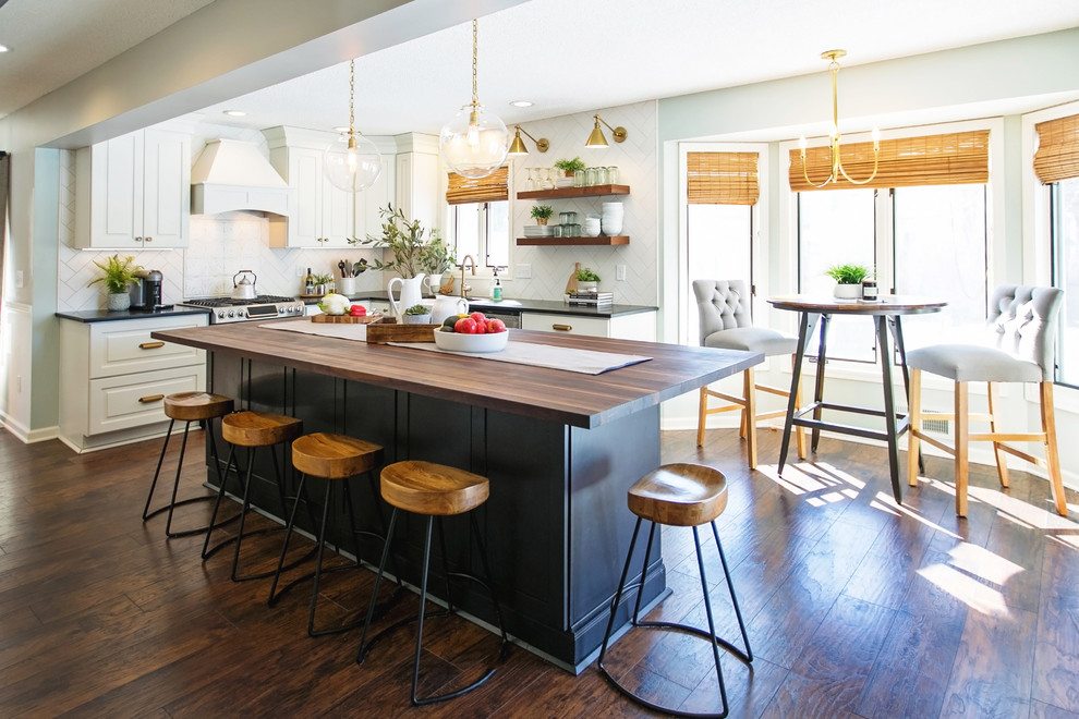 Design ideas for a large country l-shaped open plan kitchen in Atlanta with a farmhouse sink, white cabinets, wood benchtops, white splashback, porcelain splashback, stainless steel appliances, dark hardwood floors, with island, brown floor, brown benchtop and raised-panel cabinets.