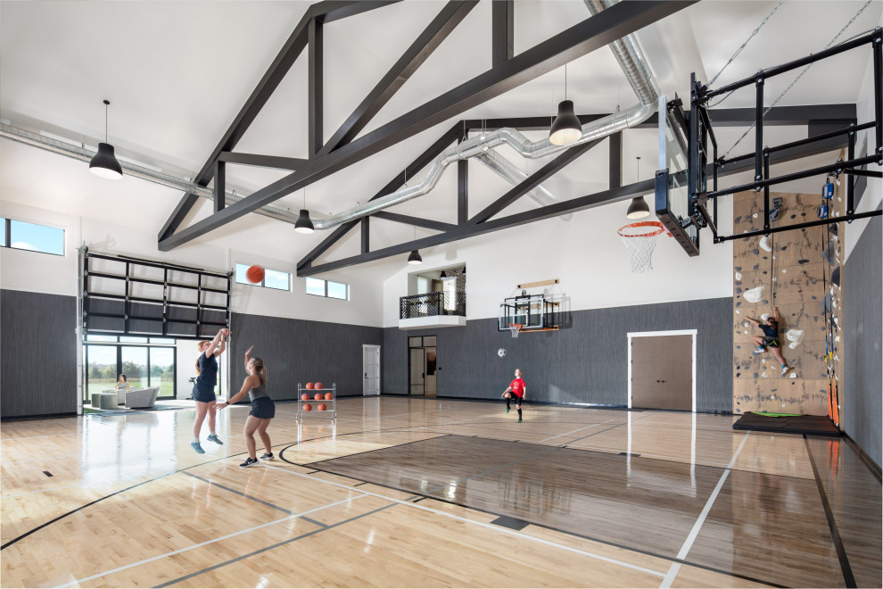 Indoor basketball/tennis/multi-game court - huge transitional light wood floor, beige floor, exposed beam and vaulted ceiling indoor basketball/tennis/multi-game court idea in Denver with white walls