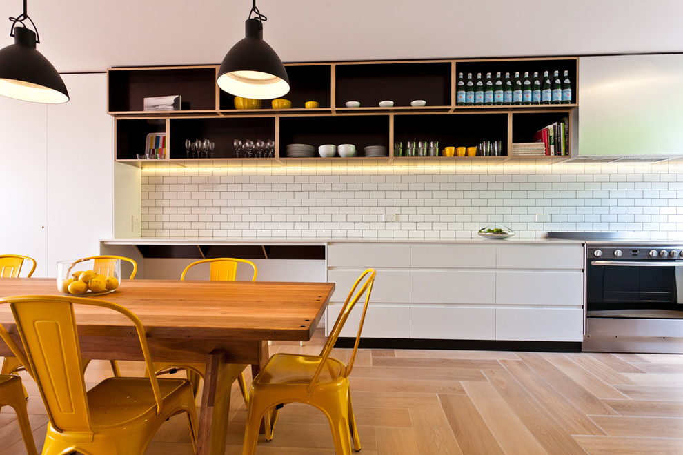 This is an example of a contemporary eat-in kitchen in Sydney with open cabinets, white cabinets, white splashback, subway tile splashback, stainless steel appliances and light hardwood floors.