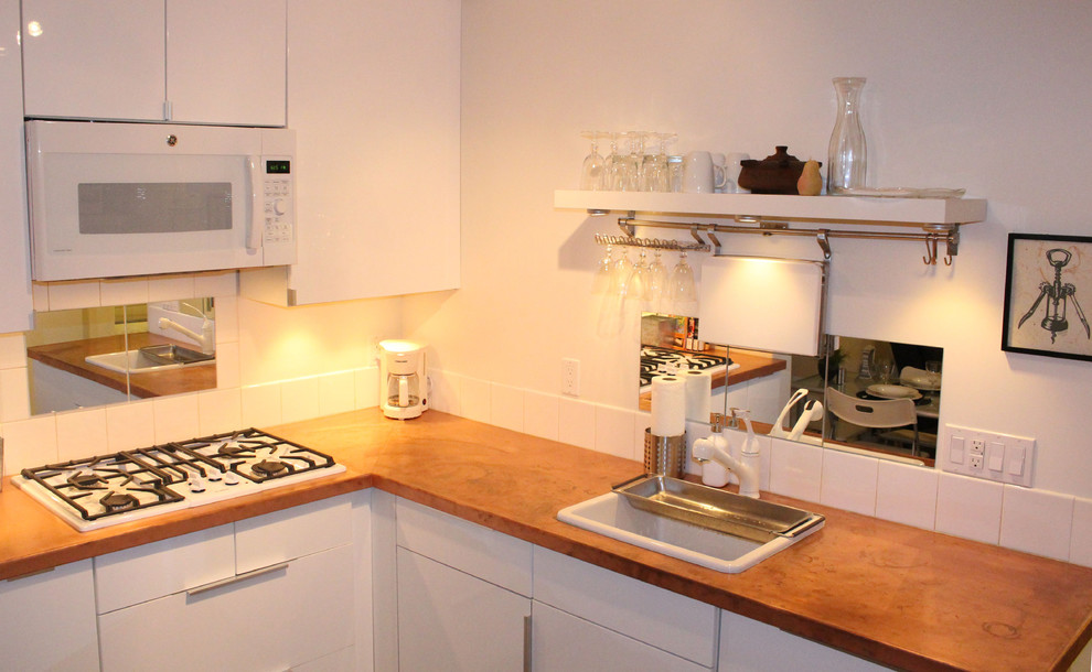 Exempel på ett litet modernt kök, med en nedsänkt diskho, släta luckor, vita skåp, bänkskiva i akrylsten, vitt stänkskydd, stänkskydd i keramik, vita vitvaror och ljust trägolv