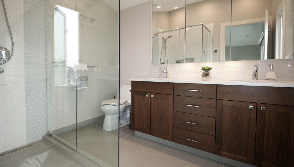 Mid-sized transitional master bathroom in Calgary with shaker cabinets, dark wood cabinets, a corner shower, a two-piece toilet, grey walls, porcelain floors, an undermount sink, engineered quartz benchtops, grey floor, a hinged shower door, white benchtops, a double vanity, a built-in vanity, white tile, subway tile and vaulted.