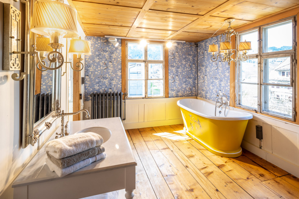 Foto di una grande stanza da bagno country con vasca freestanding, pareti blu, parquet chiaro, lavabo da incasso, top in legno, pavimento marrone, top bianco, un lavabo e carta da parati