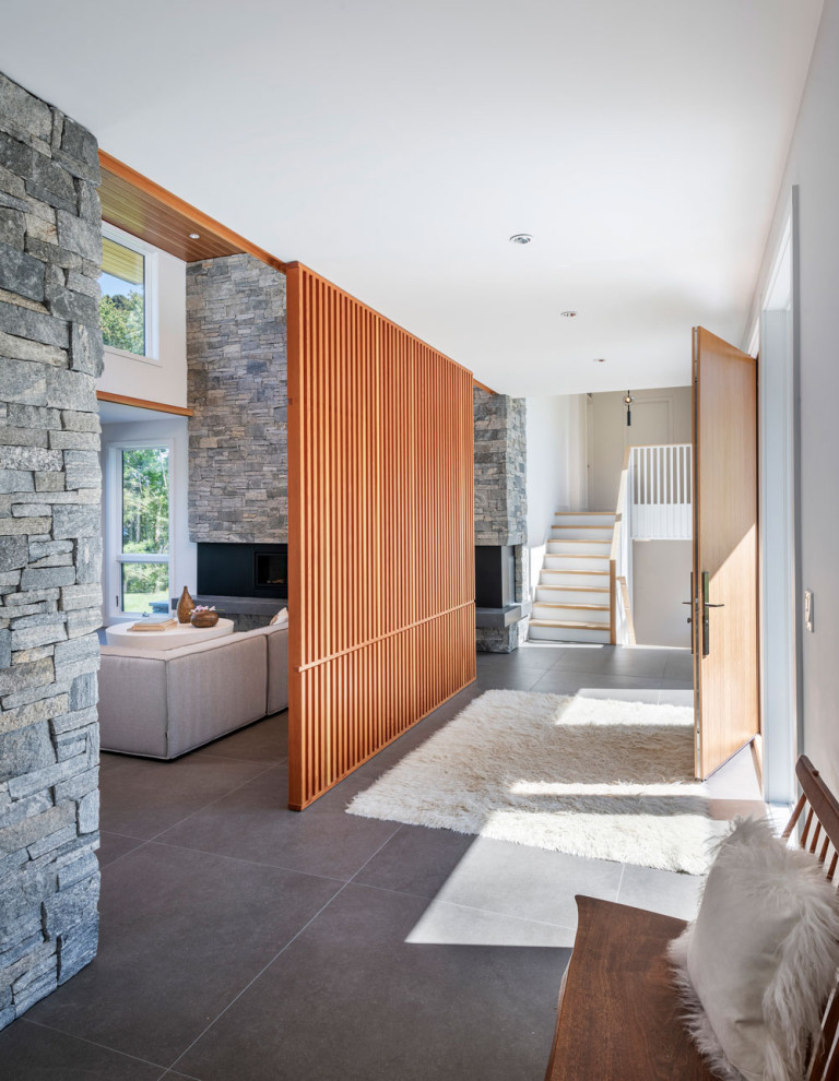 Inspiration for a midcentury entrance in Boston with white walls, ceramic flooring, a single front door, a medium wood front door, grey floors and feature lighting.