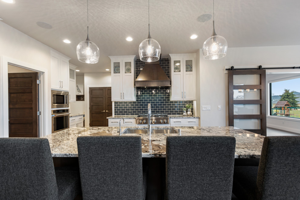 Example of a mid-sized transitional l-shaped medium tone wood floor and brown floor eat-in kitchen design with an undermount sink, shaker cabinets, white cabinets, granite countertops, blue backsplash, subway tile backsplash, stainless steel appliances, an island and multicolored countertops