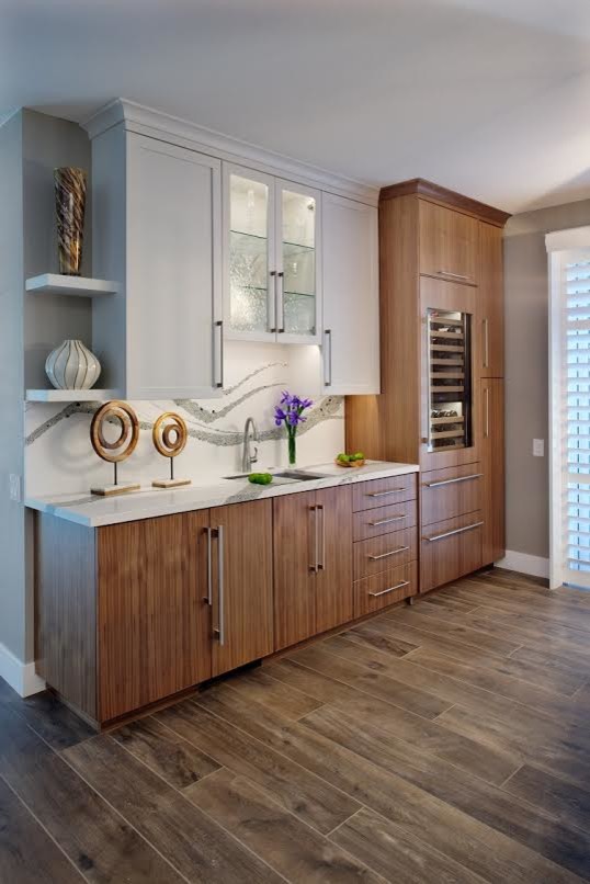 Mid-sized transitional single-wall wet bar in Sacramento with an undermount sink, flat-panel cabinets, medium wood cabinets, white splashback, brown floor, white benchtop, quartz benchtops and porcelain floors.