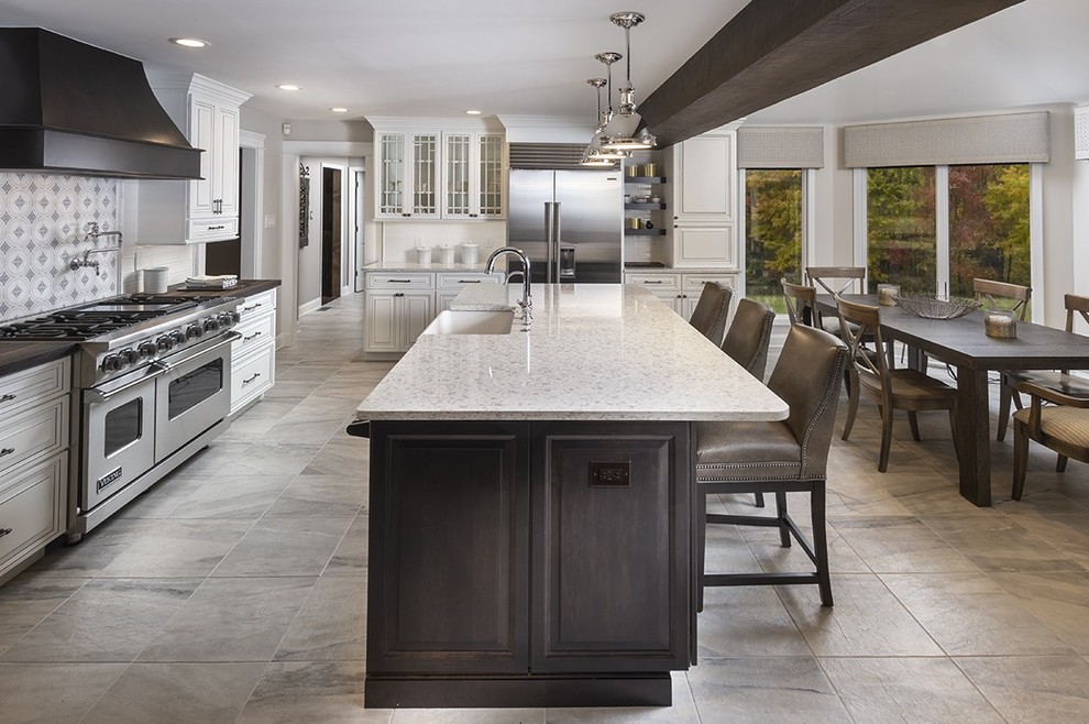 Large traditional eat-in kitchen in Philadelphia with a farmhouse sink, raised-panel cabinets, white cabinets, stainless steel appliances, ceramic floors, with island, grey floor, multi-coloured splashback, black benchtop, quartz benchtops, subway tile splashback and exposed beam.