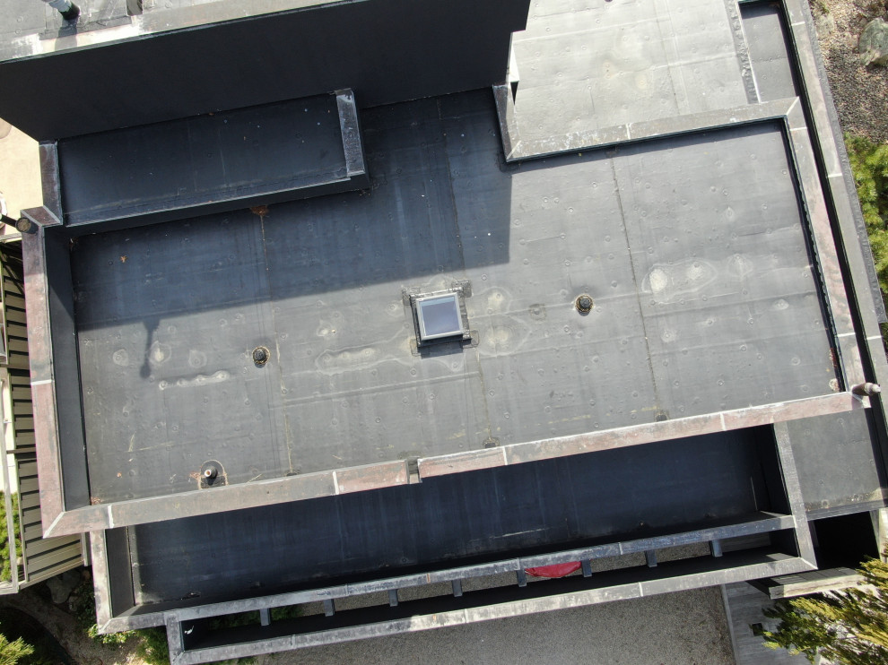 Aménagement d'une grande façade de maison grise contemporaine en panneau de béton fibré à un étage avec un toit plat, un toit mixte et un toit noir.