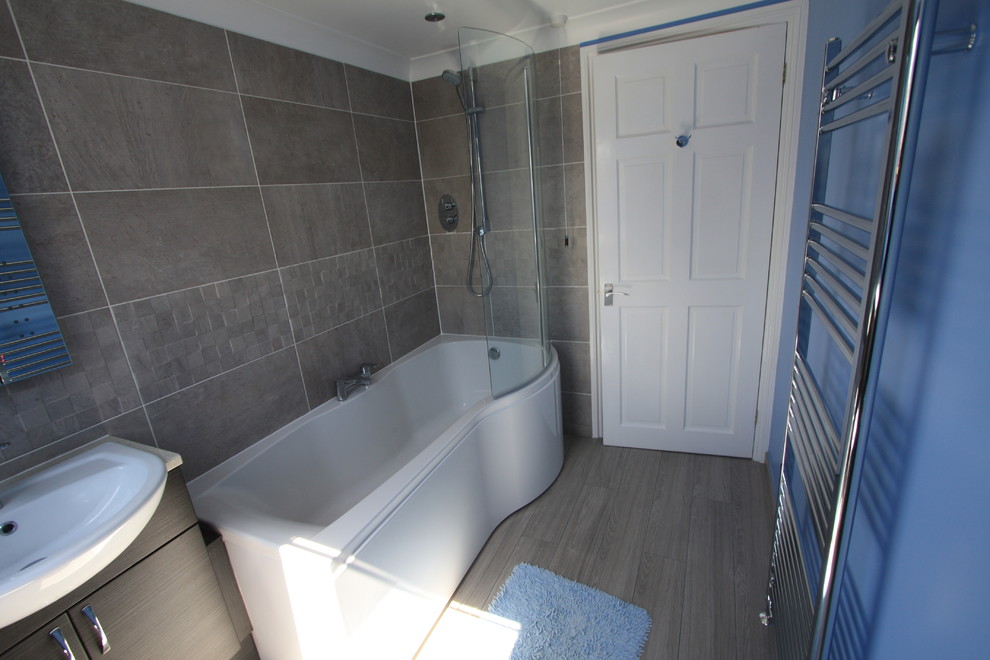 Idée de décoration pour une salle de bain principale avec un placard à porte plane, des portes de placard grises, un plan de toilette en stratifié, un carrelage gris, des carreaux de céramique, un mur bleu et un sol en bois brun.