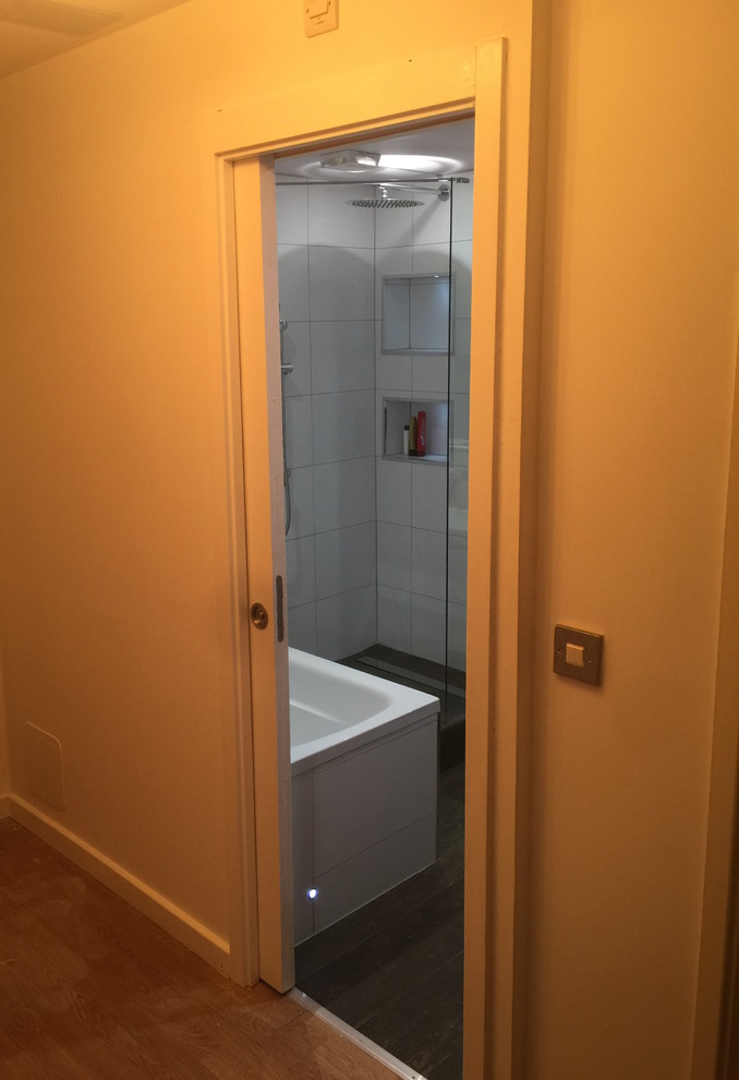 This is an example of a small contemporary kids wet room bathroom in London with flat-panel cabinets, white cabinets, a drop-in tub, a two-piece toilet, brown tile, ceramic tile, white walls, ceramic floors, a wall-mount sink and tile benchtops.