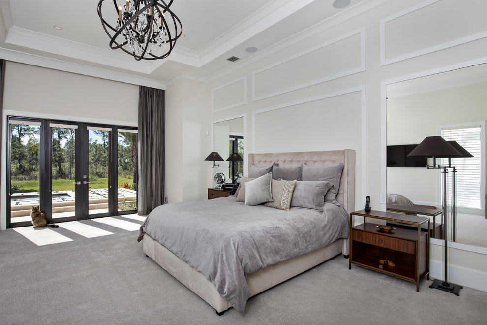 This is an example of a large contemporary master bedroom in Miami with beige walls and carpet.