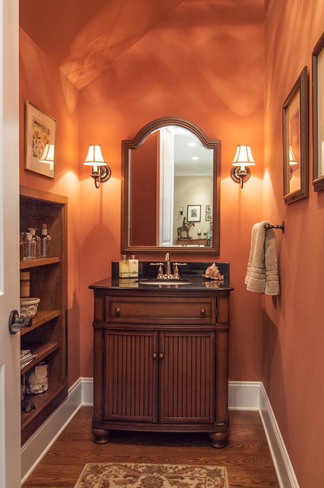 Photo of a traditional powder room in Charlotte with an undermount sink, recessed-panel cabinets and dark wood cabinets.