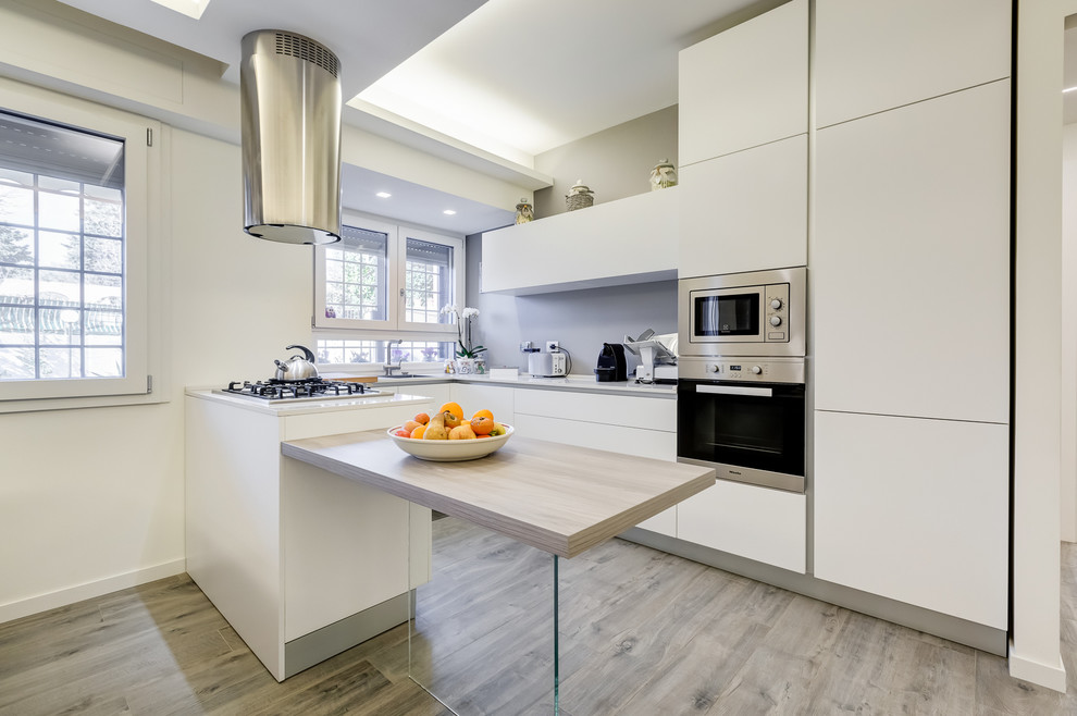 Mid-sized modern u-shaped eat-in kitchen in Rome with an integrated sink, flat-panel cabinets, grey splashback, stainless steel appliances, laminate floors, a peninsula and grey floor.