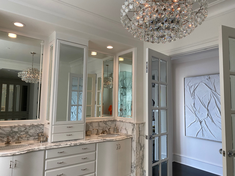 Inspiration for a large master bathroom in Orange County with furniture-like cabinets, white cabinets, a drop-in tub, a corner shower, a two-piece toilet, white tile, marble, white walls, dark hardwood floors, an undermount sink, marble benchtops, brown floor, a hinged shower door, grey benchtops, a shower seat, a double vanity, a built-in vanity, coffered and panelled walls.