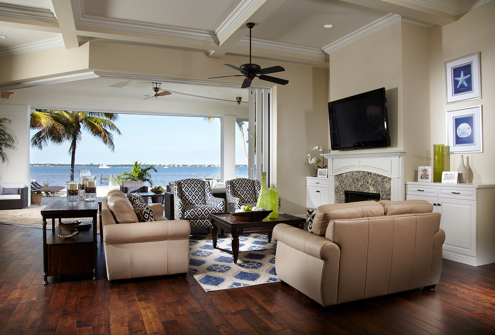 This is an example of a traditional open concept living room in Tampa with beige walls, dark hardwood floors, a standard fireplace and a wall-mounted tv.