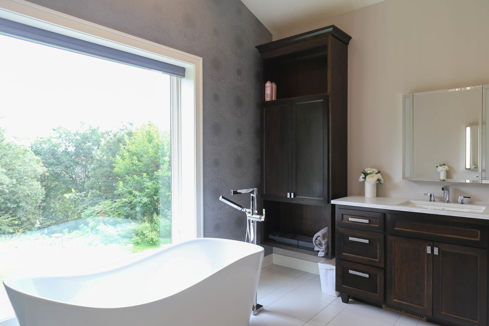 Example of a mid-sized transitional master white tile and porcelain tile porcelain tile and white floor freestanding bathtub design with recessed-panel cabinets, dark wood cabinets, a two-piece toilet, gray walls, an undermount sink, quartzite countertops, a hinged shower door and white countertops