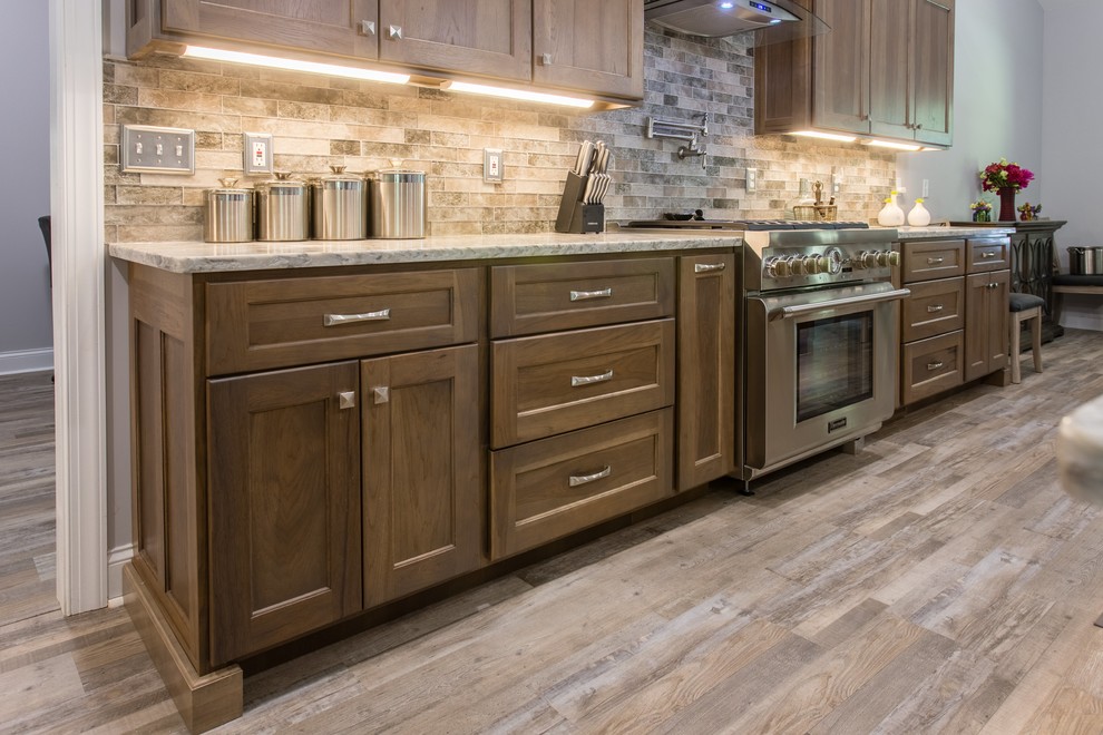 Transitional l-shaped open concept kitchen photo with shaker cabinets, stainless steel appliances and an island