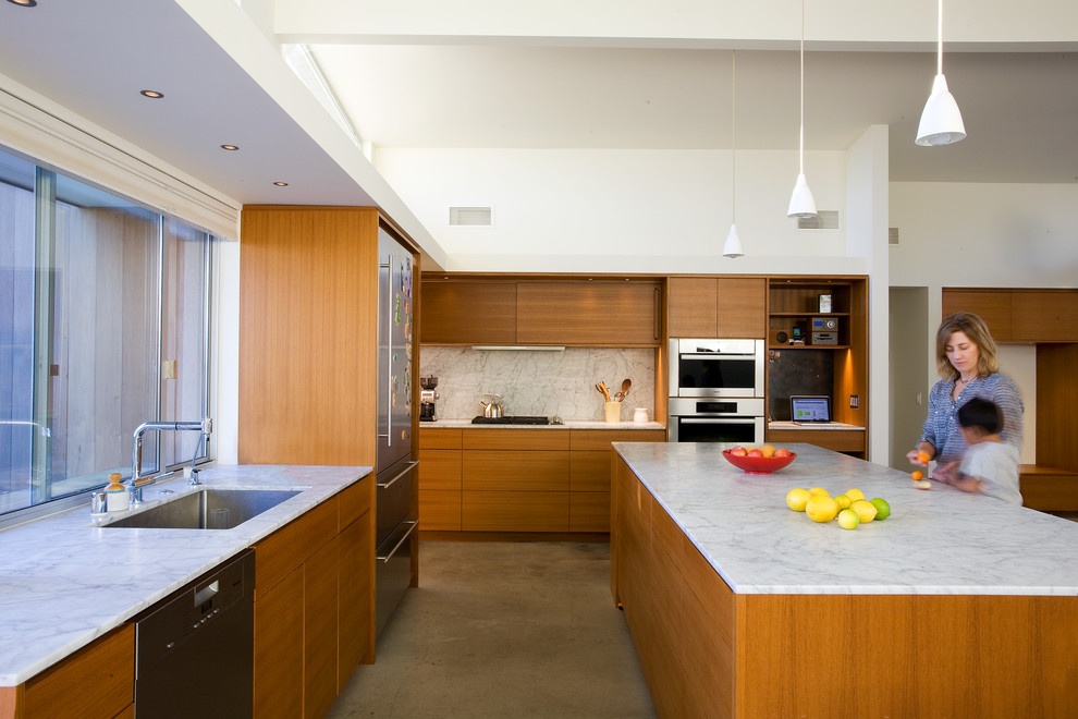 Inspiration for a midcentury l-shaped kitchen in Santa Barbara with an undermount sink, flat-panel cabinets, medium wood cabinets, white splashback, stainless steel appliances and with island.