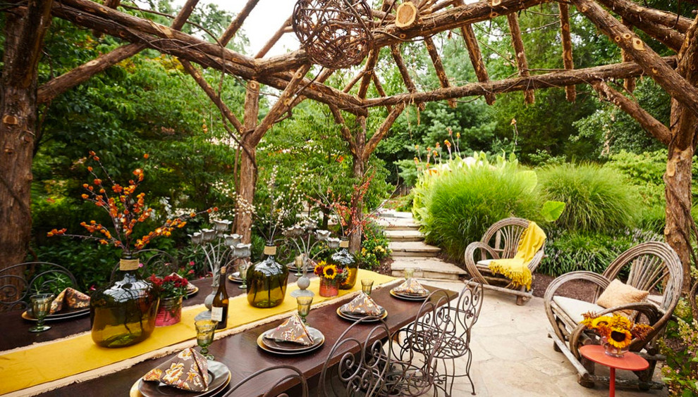 Inspiration for a large country backyard patio in St Louis with natural stone pavers and a pergola.