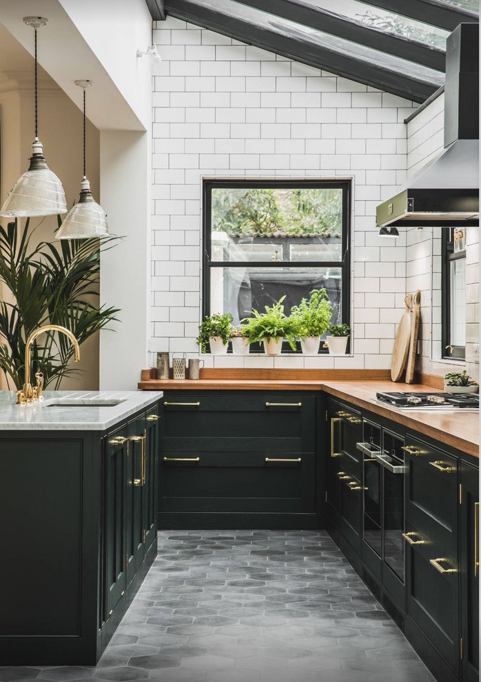 Inspiration for a mid-sized industrial l-shaped eat-in kitchen in Columbus with an undermount sink, recessed-panel cabinets, black cabinets, wood benchtops, brown splashback, timber splashback, black appliances, marble floors, with island, grey floor and brown benchtop.