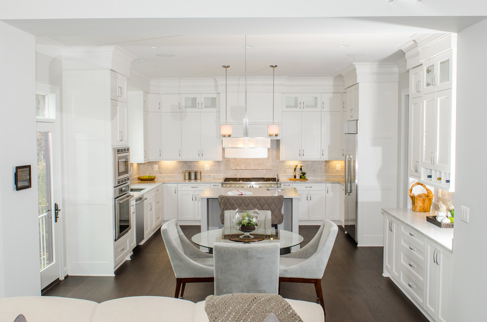 Photo of a transitional u-shaped eat-in kitchen in DC Metro with an undermount sink, shaker cabinets, white cabinets, marble benchtops, white splashback, stone tile splashback, stainless steel appliances, dark hardwood floors and with island.