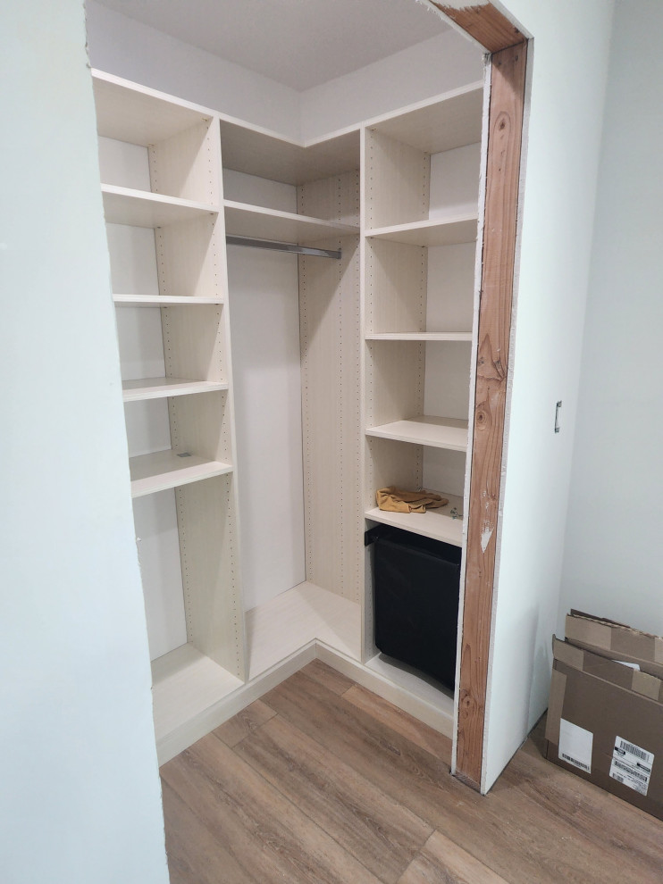 Large modern walk-in wardrobe in Los Angeles with flat-panel cabinets and light hardwood flooring.