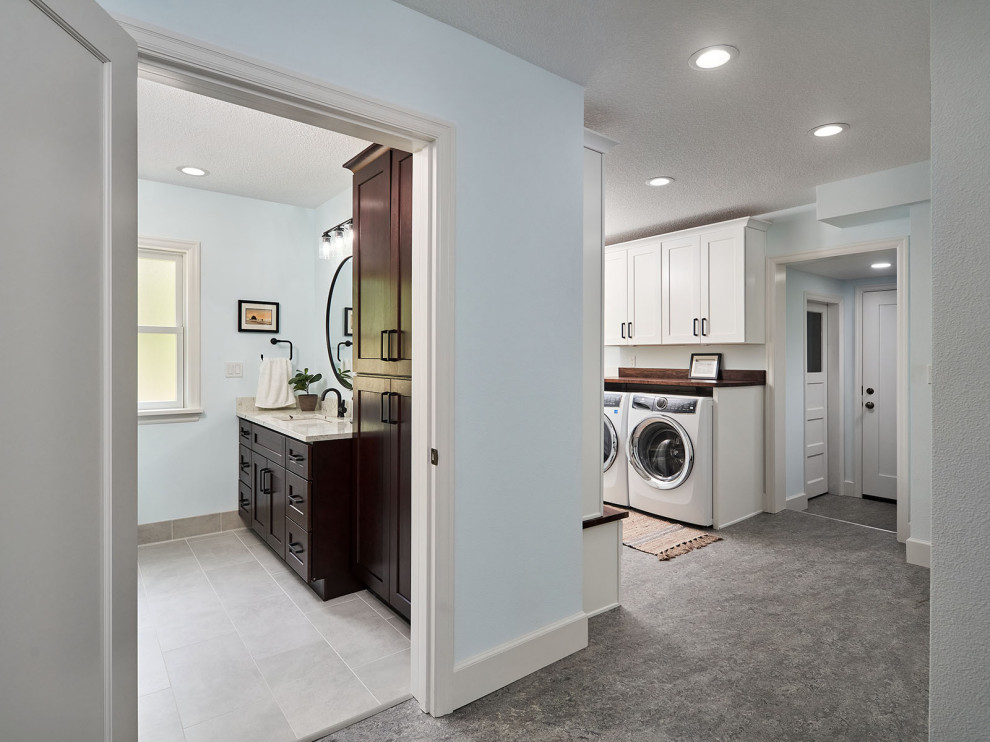 Mid-sized traditional galley utility room in Portland with an undermount sink, shaker cabinets, white cabinets, wood benchtops, timber splashback, blue walls, vinyl floors, a side-by-side washer and dryer, grey floor and brown benchtop.