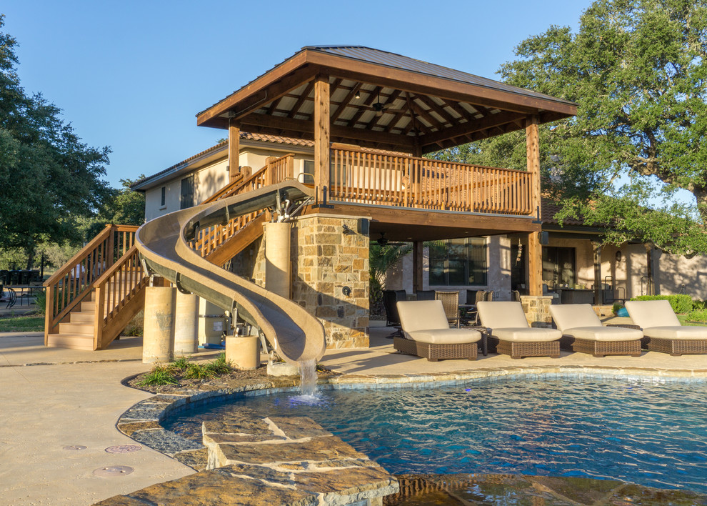 Example of a large mountain style backyard stone patio fountain design in Austin with a gazebo