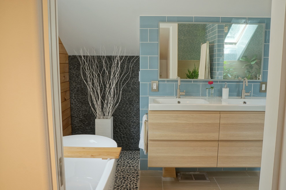 Photo of a mid-sized scandinavian master bathroom in Denver with an integrated sink, flat-panel cabinets, light wood cabinets, wood benchtops, a freestanding tub, an open shower, a one-piece toilet, blue tile, glass tile, white walls and ceramic floors.