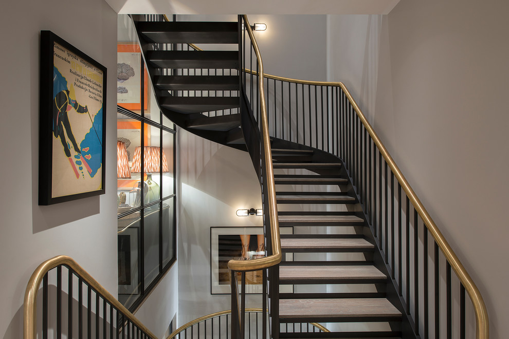 Design ideas for a modern wood curved staircase in London with open risers and metal railing.
