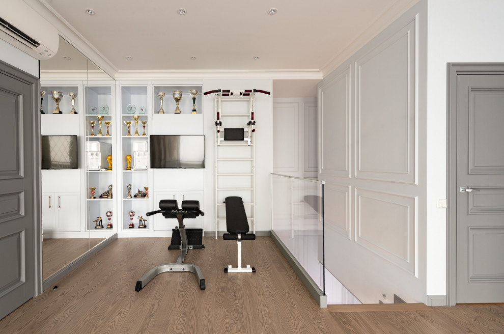 Immagine di una palestra in casa classica con pareti bianche, pavimento in legno massello medio e pavimento marrone