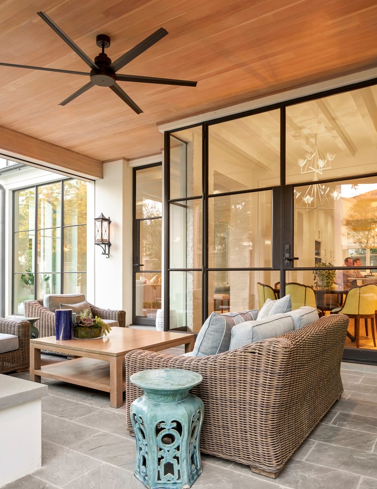 This is an example of a large transitional stone back porch design in Dallas with a roof extension.