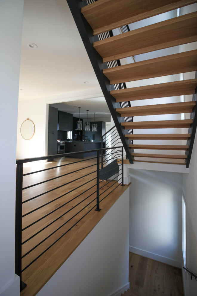 This is an example of a mid-sized contemporary wood straight staircase in DC Metro with metal railing.