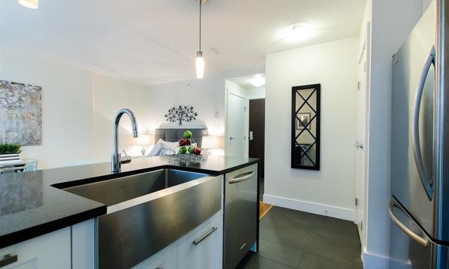 Small contemporary single-wall open plan kitchen in Vancouver with shaker cabinets, white cabinets, with island, terrazzo benchtops, a farmhouse sink, stainless steel appliances and porcelain floors.