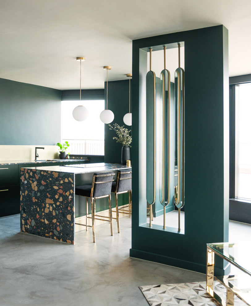 Mid-sized eclectic u-shaped open plan kitchen in London with a single-bowl sink, flat-panel cabinets, green cabinets, terrazzo benchtops, metallic splashback, black appliances, concrete floors, a peninsula, grey floor and multi-coloured benchtop.