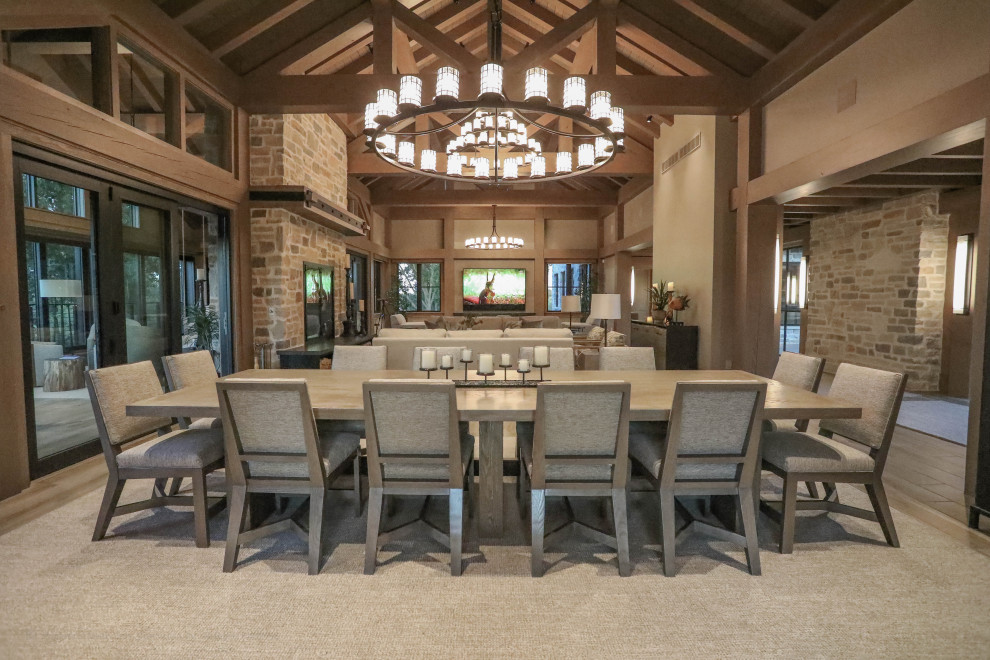 Inspiration for an expansive country formal open concept living room with beige walls, porcelain floors, a two-sided fireplace, a stone fireplace surround, a wall-mounted tv and exposed beam.
